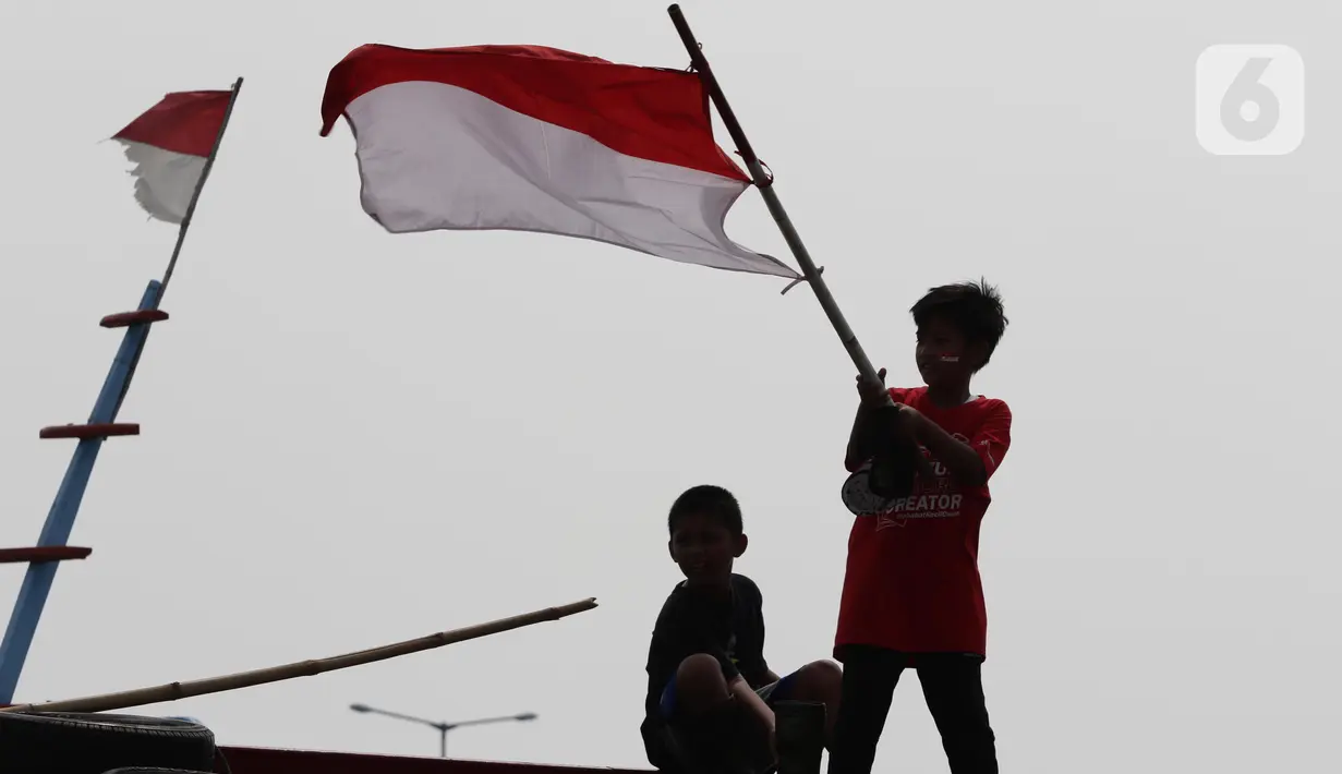Dua orang anak mengibar-ngibarkan bendera Merah Putih usai pelaksanaan Upacara Peringatan HUT RI ke-77 di Kawasan Kalibaru Barat, Cilincing, Jakarta, Rabu (17/8/2022). Memperingati Hari Kemerdekaan Indonesia ke-77, anak-anak yang tergabung dalam Kelas Jurnalis Cilik bersama para relawan melaksanakan upacara bendera dan beragam lomba. (Liputan6.com/Helmi Fithriansyah)