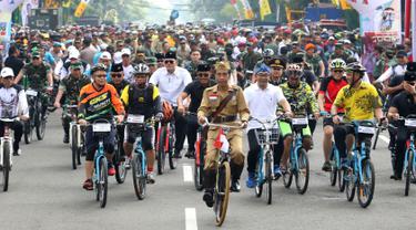Presiden Joko Widodo atau Jokowi (tengah) didampingi Gubernur Jawa Barat Ridwan Kamil (kanan) saat mengikuti Bandung Lautan Sepeda, Sabtu (10/11). Jokowi menaiki sepeda ontel dalam kegiatan tersebut. (Liputan6.com/Angga Yuniar)