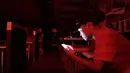 Seorang karyawan di restoran cepat saji bermain ponsel selama pemadaman listrik di San Juan, Puerto Rico, Rabu (21/9). Kebakaran telah memutus dua jalur transmisi listrik dan mengakibatkan kegagalan penyaluran tenaga ke seluruh pulau. (REUTERS/Alvin Baez)