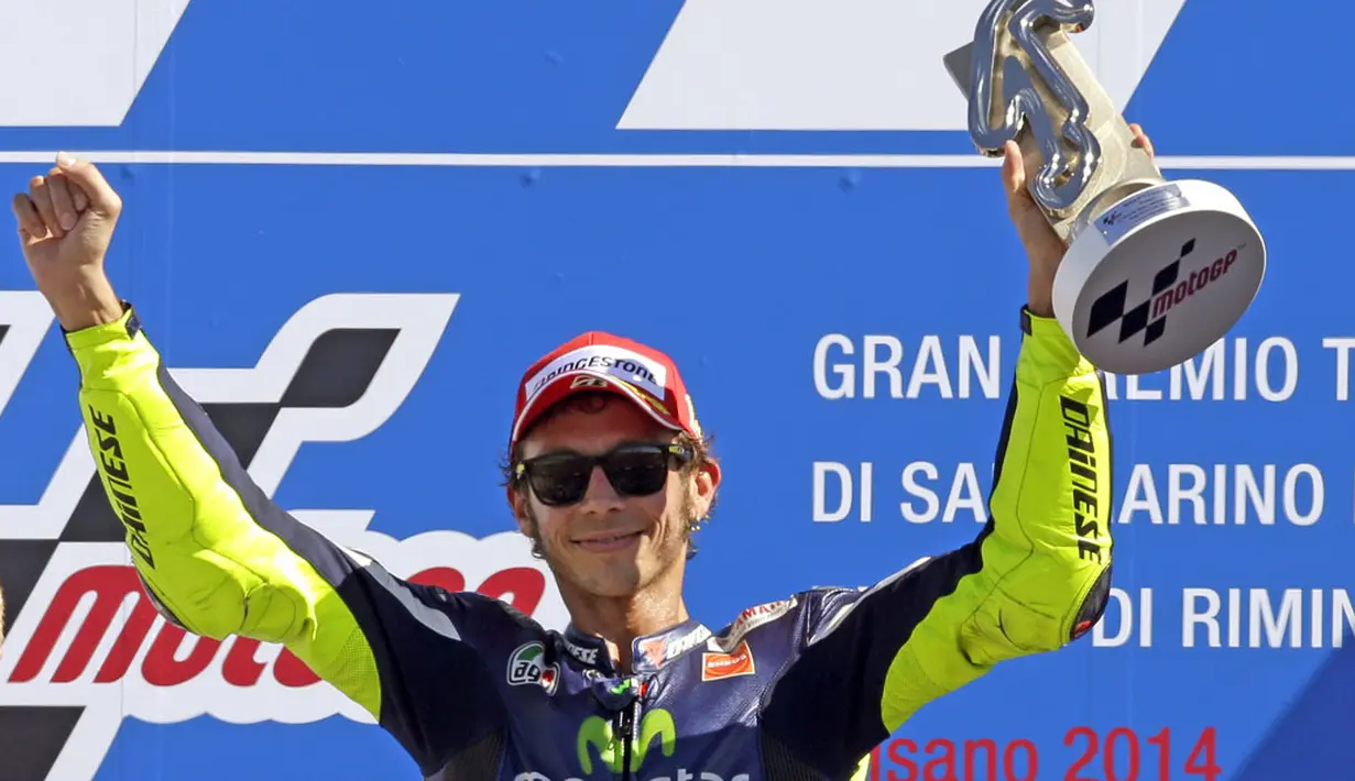 Pembalap Yamaha MotoGP, Valentino Rossi, mengangkat trofi kemenangan usai menjadi kampiun di Grand Prix San Marino, Italia, (14/9/2014). (REUTERS/Max Rossi)