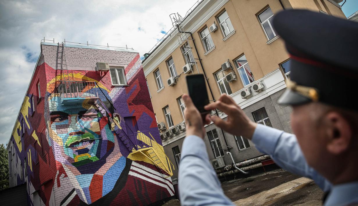 Petugas keamanan memotret mural bergambar bintang Portugal, Cristiano Ronaldo, yang dibuat untuk menyambut Piala Konfederasi di Kazan, Kamis (15/6/2017). (EPA/Mario Cruz)