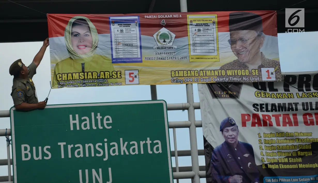 Petugas Satpol PP mencopot Alat Peraga Kampanye (APK) Pilpres, Caleg dan Partai Politik di Kawasan Jalan Pemuda, Jakarta, Rabu (13/3). APK Pemilu 2019 yang terpasang pada JPO dibersihkan. (merdeka.com/Imam Buhori)