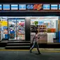 Seorang pria berjalan melewati toko serba ada atau convenience store GS25 di sepanjang jalan di Seoul pada 18 Agustus 2023. (ANTHONY WALLACE / AFP)