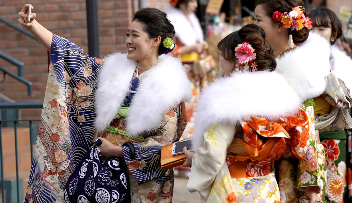 Dengan balutan kimono, empat wanita Jepang berpose saat mengikuti Coming of Age Day atau Hari Kedewasaan di Toshimaen, Tokyo, Jepang, Senin, (8/1). Hari Kedewasaan bisa diselenggarakan oleh pemerintah, sekolah maupun  swasta. (AP Photo/Shizuo Kambayashi)