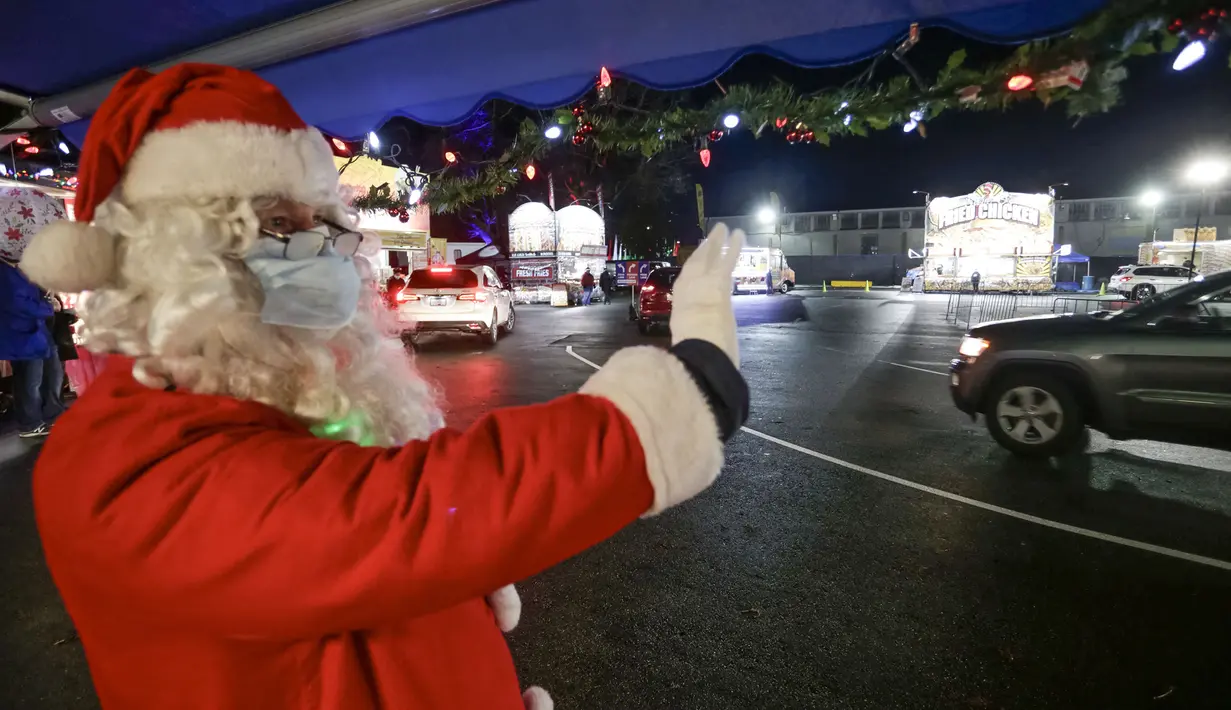 Penampil berkostum Sinterklas berinteraksi dengan pengunjung dalam acara drive-thru "WinterLights" di Pacific National Exhibition, Vancouver, British Columbia, Kanada, 12 Desember 2020. Acara ini untuk menyebarkan kegembiraan Natal kepada masyarakat di tengah pandemi COVID-19. (Xinhua/Liang Sen)