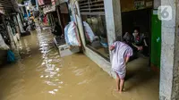 Warga membersihkan barang-barang yang terendam banjir di permukiman kawasan Kampung Melayu, Jakarta, Selasa (9/2/2021). Banjir yang berangsur surut dimanfaatkan warga untuk membersihkan rumah dan barang-barang dari endapan lumpur. (Liputan6.com/Faizal Fanani)
