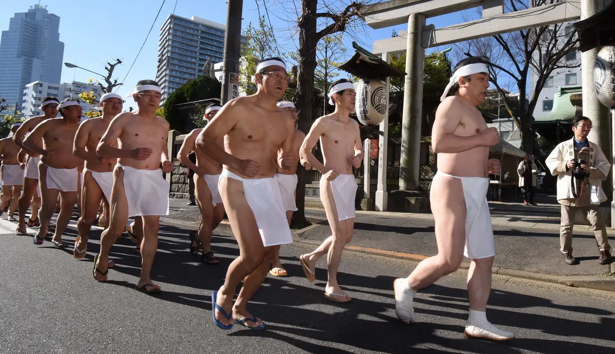 Penganut Shinto melakukan pemanasan sebelum memasuki kolam renang es untuk berdoa dan memurnikan tubuh dan jiwa dalam ritual Upacara Penyucian di Tokyo, Minggu (10/01/2016). (AFP Photo/ Toru Yamanaka)