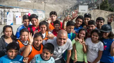 Mantan pemain bola Juventus, David Trezeguet berfoto bersama anak-anak di komunitas San Pablo Mirador, Peru (13/7). Trezeguet melakukan kunjungan ke Peru untuk mempromosikan Paris yang menjadi tuan rumah Olimpiade 2024. (AFP Photo/Ernesto Benavides)