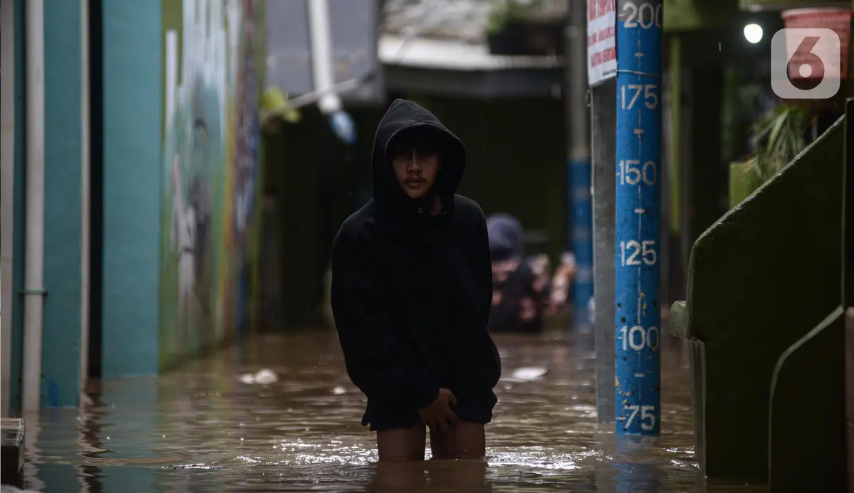 Warga melintasi banjir di kawasan Kebon Pala, Kampung Melayu, Jakarta Timur, Sabtu (16/7/2022). Karena rumahnya terendam banjir, sejumlah warga sudah mulai menyelamatkan barang-barang berharga ke tempat yang lebih tinggi. (merdeka.com/Imam Buhori)