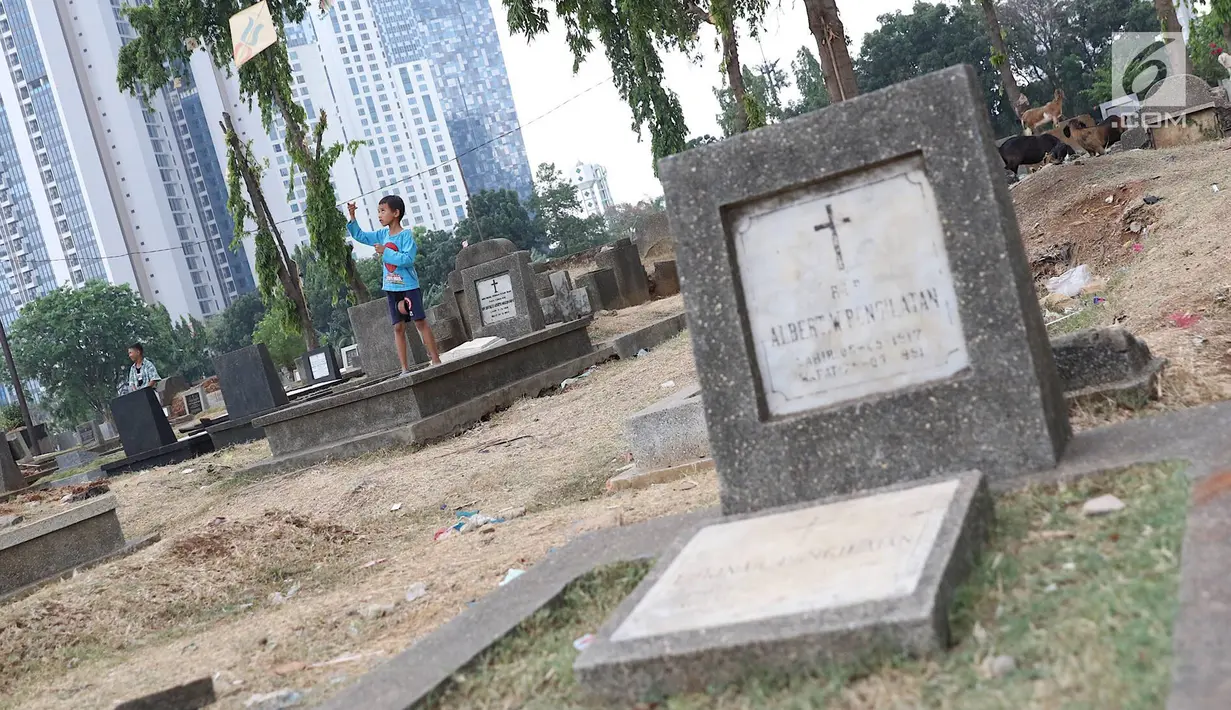 Seorang anak bermain layangan di TPU Menteng Pulo, Jakarta, Kamis (18/10). Padatnya pemukiman penduduk serta gedung bertingkat di kawasan tersebut menyebabkan anak-anak terpaksa bermain di tempat yang tidak semestinya. (Liputan6.com/Immanuel Antonius)