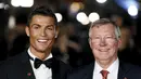 Penyerang Real Madrid, Cristiano Ronaldo bersama Sir Alex Ferguson tersenyum saat difoto dalam pemutaran film perdana 'Ronaldo' di Leicester Square, London, Inggris (9/11). (Reuters/Stefan Wermuth)