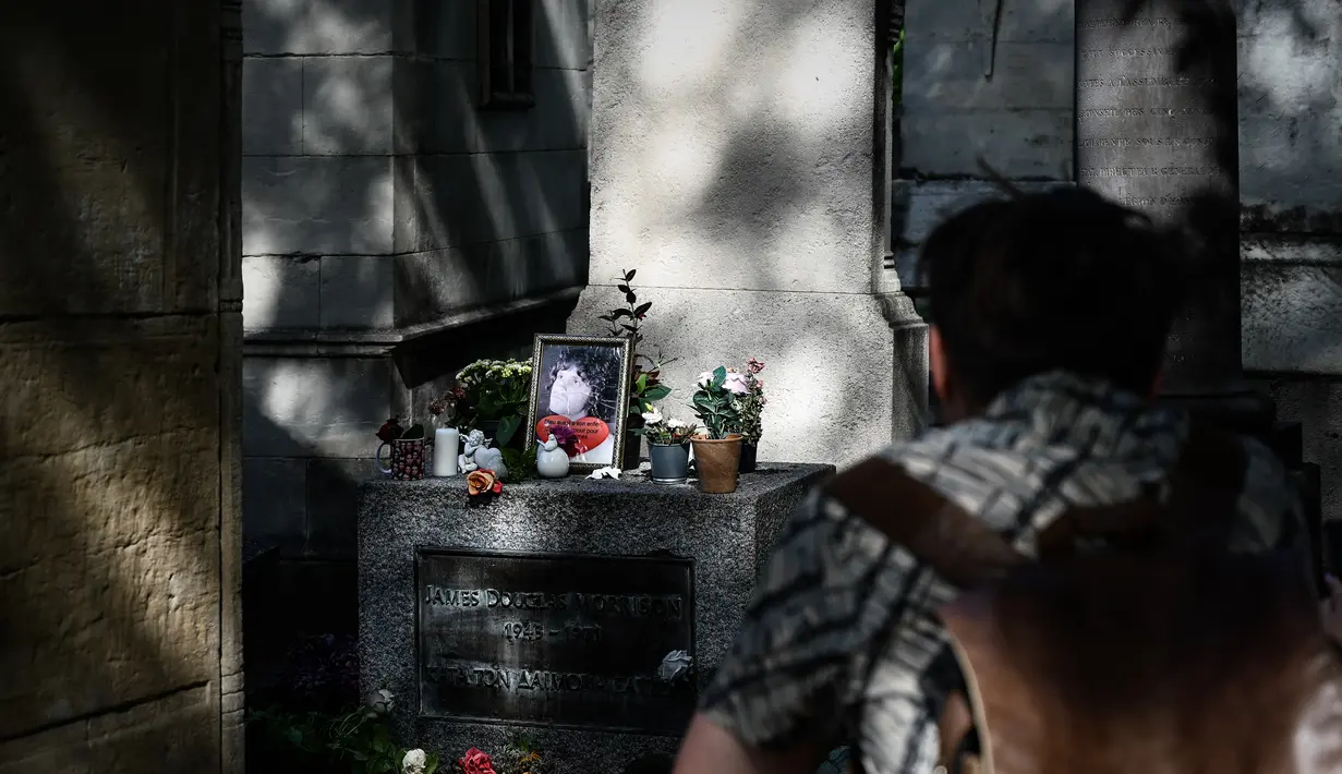 Seorang pria melihat makam almarhum bintang rock AS Jim Morrisson di pemakaman Pere Lachaise selama di Paris (22/7/2019). Pemakaman ini dibuka pada tahun 1804. (AFP Photo/Philippe Lopez)
