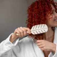 Seorang perempuan menyisir rambut keritingnya (Foto Dok: Freepik/freepik).