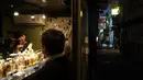 Pemilik bar Marie Yoshida (kiri) mengobrol dengan pengunjung di barnya di Golden Gai di distrik Shinjuku Tokyo (28/7/2019). Lebih dari 200 bar kecil bergaya klub dan restoran di area ini. (AP Photo / Jae C. Hong)
