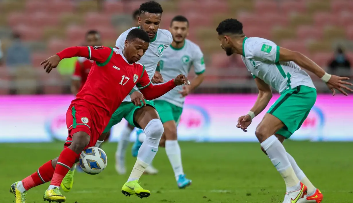 Pemain Oman Arshad al-Alawi (kiri) dibayangi pemain Arab Saudi Ali al-Bulaihi (tengah) pada pertandingan sepak bola Kualifikasi Piala Dunia 2022 di Stadion King Abdullah Sport City, Jeddah, Arab Saudi, 27 Januari 2022. Arab Saudi menang 1-0. (AFP)