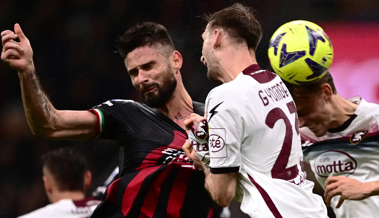 Striker AC Milan, Olivier Giroud (kiri) melepaskan sundulan yang menghasilkan gol ke gawang Salernitana pada laga pekan ke-26 Liga Italia 2022/2023 di San Siro Stadium, Milan, Selasa (14/3/2023) dini hari WIB. (AFP/Marco Bertorello)