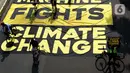 Pesepeda melintas di atas banner yang dibentangkan aktivis Greenpeace dan Bike2Work di Jalan Jenderal Sudirman, Jakarta, Minggu (5/6/2022). Aksi untuk mengkampanyekan penggunaan sepeda sebagai kendaraan ramah lingkungan dan solusi pembangunan Jakarta Kota Ramah Pesepeda. (Liputan6.com/Helmi Fithriansyah)