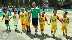 Kurniawan Dwi Yulianto bersama peserta MILO Football Clinic Day memasuki lapangan sepak bola di Lapangan Sepakbola Pertamina-Simprug, Jakarta (29/10). Sebanyak 600 siswa Sekolah Dasar di Jakarta ikut dalam pelatihan sepak bola. (Liputan6.com/Istimewa)