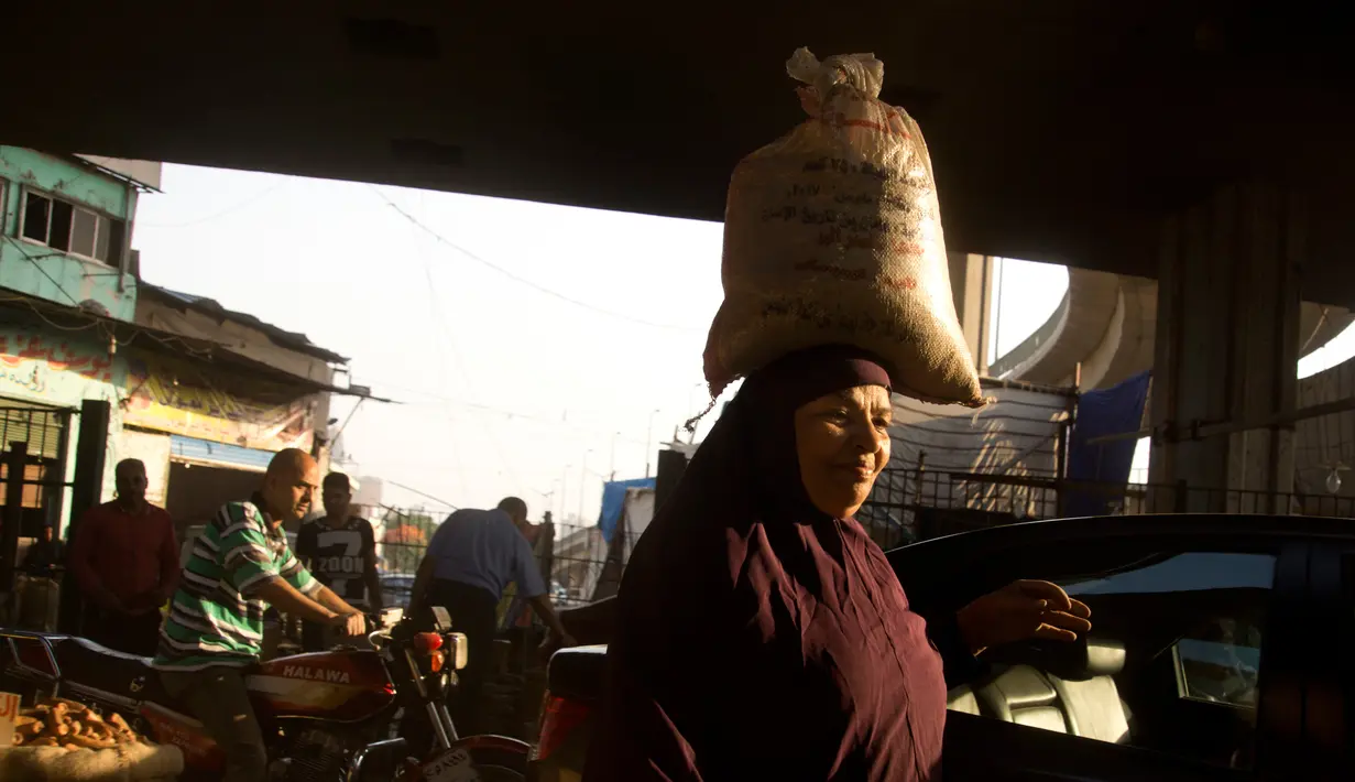 Seorang wanita membawa barang belanjaannya di sebuah pasar di Kairo, Mesir (24/5). Umat muslim di seluruh dunia bersiap untuk merayakan datangnya bulan suci Ramadan. (AP Photo / Amr Nabil)