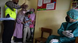 Orangtua, guru, dan polisi mencoba menenangkan seorang siswa saat akan disuntik pada kampanye vaksinasi COVID-19 di sebuah sekolah untuk anak-anak berkebutuhan khusus di Depok, Jawa Barat, Selasa (11/1/2022). Kampanye vaksinasi ini dilakukan oleh Polri. (AP Photo/Dita Alangkara)