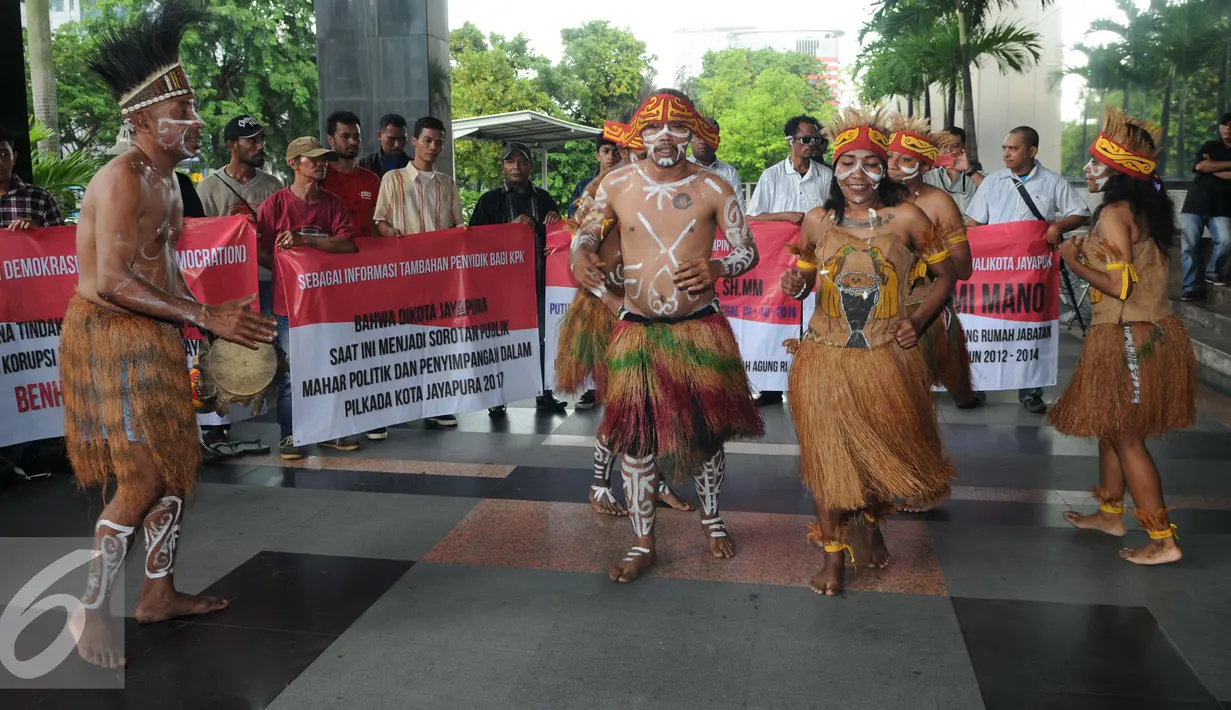 Sejumlah pemuda Papua mengenakan pakaian adat menari saat menggelar unjuk rasa di depan Gedung KPK, Jakarta, Senin (19/12). Mereka meminta KPK mengusut kasus korupsi pejabat yang mencalonkan diri pada Pilkada Jayapura 2017. (Liputan6.com/Helmi Affandi)
