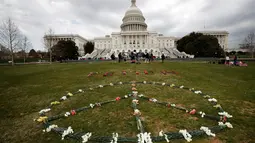 Ribuan bunga dirangkai membentuk kata "Yaman" di halaman rumput Gedung Capitol (kantor kongres) AS, Senin (19/3). 5000 bunga diletakkan mengenang ribuan anak yang tewas akibat pengeboman oleh koalisi pimpinan Arab Saudi di Yaman. (AP/Jacquelyn Martin)