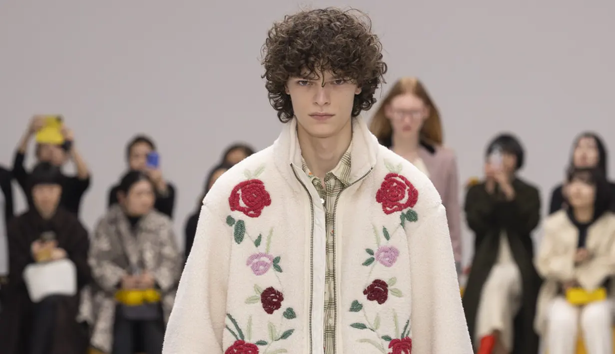 Di atas runway, koleksi menampilkan perpaduan formalwear, casualwear, workwear, dan sportswear yang menghasilkan kombinasi baru yang tak terduga. Gaun dengan aksen pita horizontal dipadukan hoodie bermotif herringbone, sementara gaun plisket hijau apel tampil kontras dengan rompi korduroi bertekstur dan kantong besar. Look lain menghadirkan blus kotak kotak ringan dengan motif bunga yang dipadukan rok midi kuning oker berbahan menyerupai bulu serta pita biru langit di pinggang. Nuansa romantis juga muncul melalui fleece hijau apel yang dikenakan di atas blus merah muda berpita, dipadukan rok mini rajut. [Dok/Onitsuka Tiger].