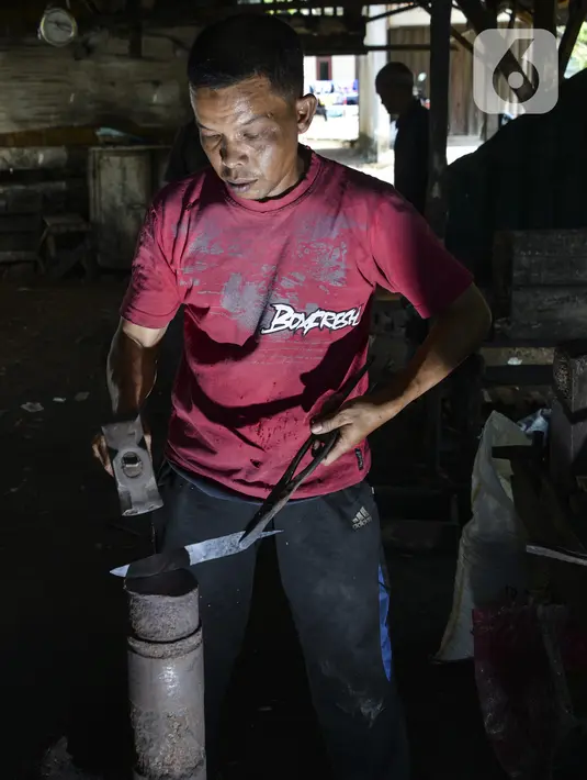 Seorang pandai mengetok baja untuk membuat pisau di bengkel tradisional di Darul Imarah, provinsi Aceh (4/11/2019). Lebih 70 persen warga di desa ini memiliki bekerja sebagai pengrajin pandai besi. (AFP Photo/Chaideer Mahyuddin)