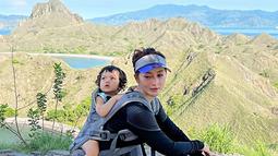 Liburan ke Labuan Bajo. Eva bersama suami dan anaknya ini menikmati indahnya pemandangan alam. Tampil sporty, Eva yang kini sudah berusia 36 tahun ini jalan-jalan sambil menggendong si kecil. (Liputan6.com/IG/@eva_anindita_zachrie)