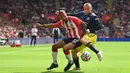 Pemain Manchester United Luke Shaw (kanan) berebut bola dengan pemain Southampton Theo Walcott (tengah) pada pertandingan Liga Inggris di Stadion St Mary, Southampton, Inggris, 22 Agustus 2021. Pertandingan berakhir imbang 1-1. (Glyn KIRK/AFP)