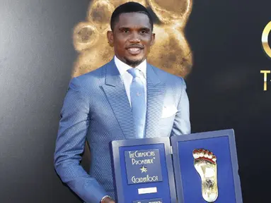 Pemain Kamerun, Samuel Eto'o berpose dengan trofi Golden Foot miliknya, Monaco, Senin (21/9/2015). Golden Foot 2015 diraih lima orang yaitu Rinat Dasaev, Daniel Passarella, Gheorghe Hagi,  Trezeguet dan Eto'o. (AFP Photo/Valery Hache)