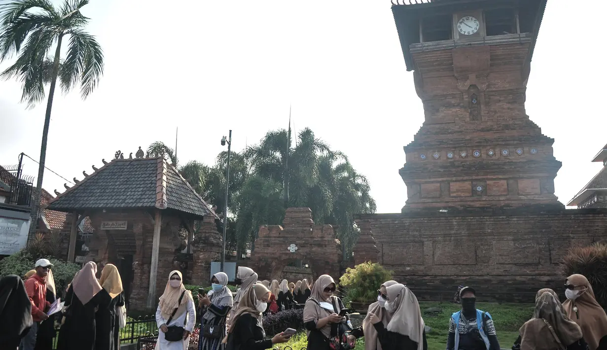 Peziarah bersantai di dekat Menara Kudus, Kauman, Kabupaten Kudus, Jawa Tengah, Rabu (30/3/2022). Menara berusia 473 tahun yang dahulu berfungsi sebagai tempat mengumandangkan azan menjadi lokasi favorit pengunjung untuk bersantai usai berziarah di Makam Sunan Kudus. (merdeka.com/Iqbal S. Nugroho)
