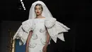 Model Gigi Hadid memakai koleksi Moschino Spring-Summer 2020 selama pekan mode di Milan, Italia (19/9/2019). Gigi tampil anggun dengan sentuhan apik pada balutan gaun pengantin berwarna putih untuk showcase unik yang terinspirasi oleh Alice In Wonderland. (AP Photo/Luca Bruno)