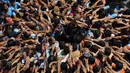 Umat Hindu membentuk piramida manusia selama Festival Janmashtami di Mumbai, India, 24 Agustus 2019. Piramida manusia itu untuk memecahkan pot berisikan suus yang menggangtung di langit-langit rumah supaya bisa diambil isinya. (AP Photo/Rajanish Kakade)