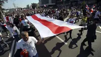 Pendukung oposisi Belarusia menggelar pawai bendera nasional saat berunjuk rasa di Minsk, Belarusia, Minggu (30/8/2020). Puluhan ribu demonstran berkumpul untuk menuntut agar Presiden Belarusia Alexander Lukashenko mengundurkan diri. (AP Photo)