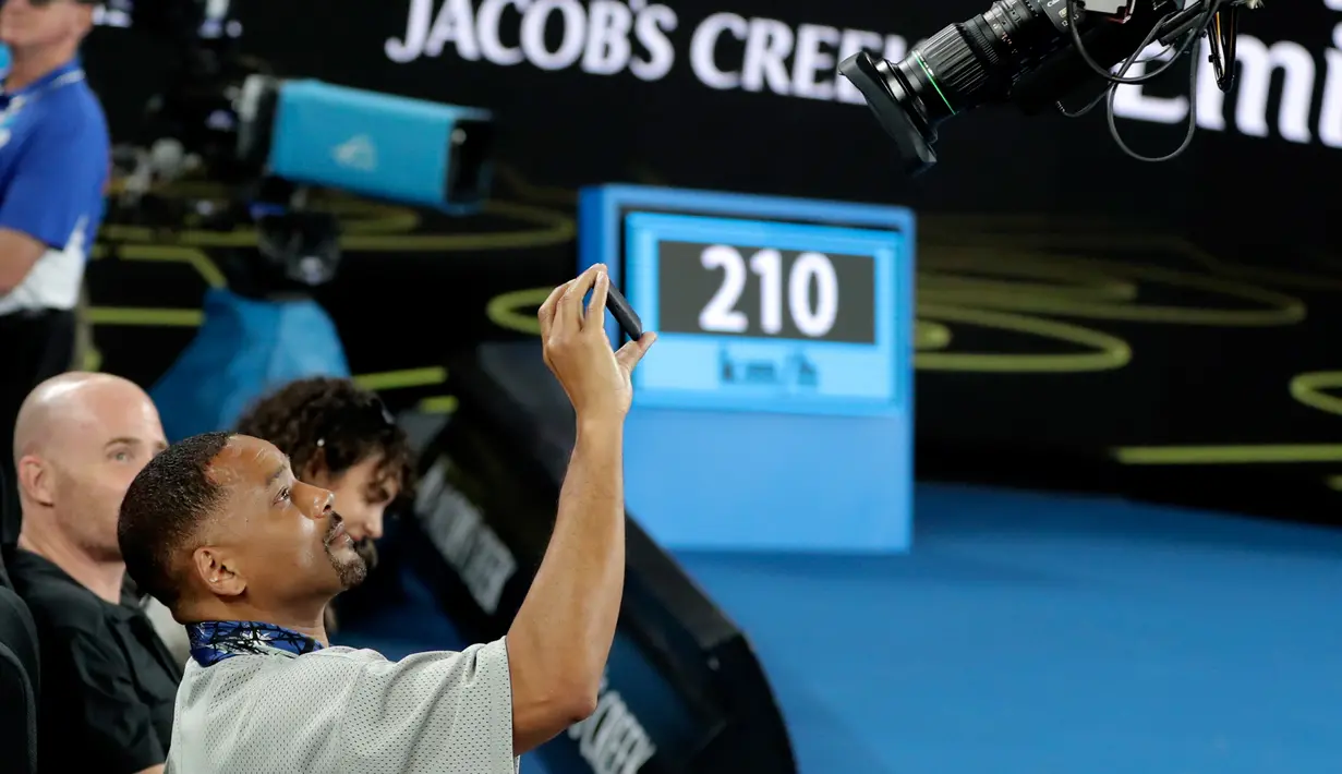 Aktor AS Will Smith mengambil foto disela pertandingan putaran ketiga antara petenis Prancis Jo-Wilfried Tsonga melawan petenis Australia Nick Kyrgios di Australia Terbuka di Melbourne, Australia (19/1). (AP Photo/Dita Alangkara)