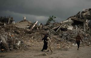 Warga Palestina berjalan melewati reruntuhan di tengah cuaca buruk Kota Gaza, Kamis 11 Desember 2025. Bencana baru mengancam ratusan ribu warga Palestina yang mengungsi di Jalur Gaza. (AP Photo/Jehad Alshrafi)