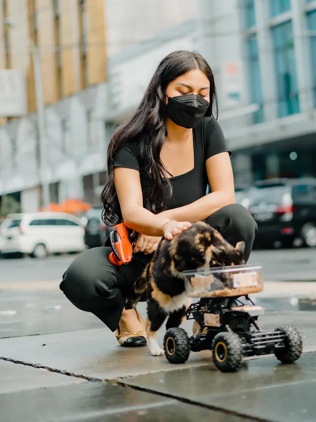 [Fimela] Ariel Tatum beri makan kucing liar di jalan