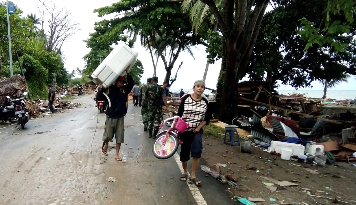 Penduduk mengungsi dari rumah-rumah yang rusak setelah tsunami menerjang Pantai Carita, di perairan Banten, Minggu (23/12). Data sementara jumlah korban dari bencana tsunami di Selat Sunda tercatat 43 orang meninggal dunia. (SEMI / AFP)