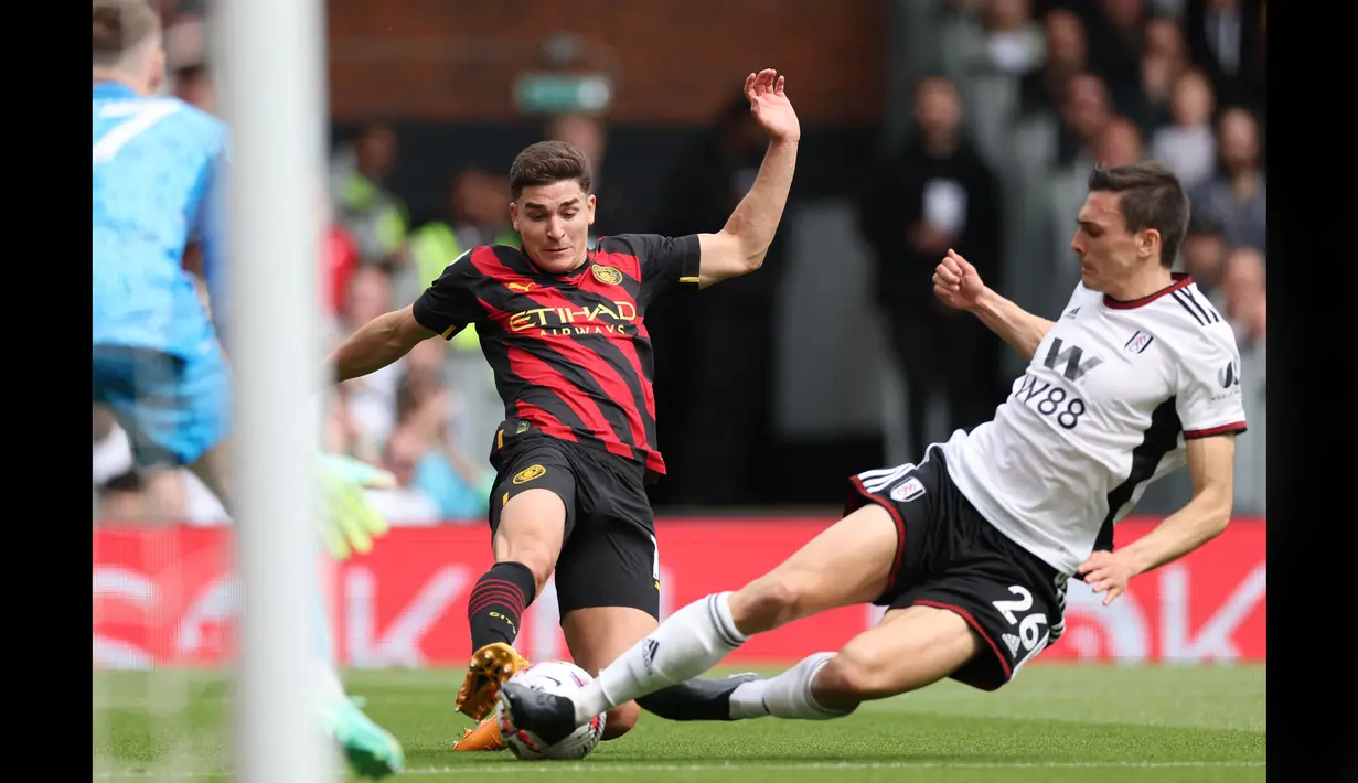 Pemain Manchester City, Julian Alvarez (kiri), berusaha mengecoh pemain Fulham, Joao Palhinha, dalam pertandingan pekan ke-34 Premier League 2022/2023 yang berlangsung di Craven Cottage, Minggu (30/4/2023). (AFP/Adrian Dennis)