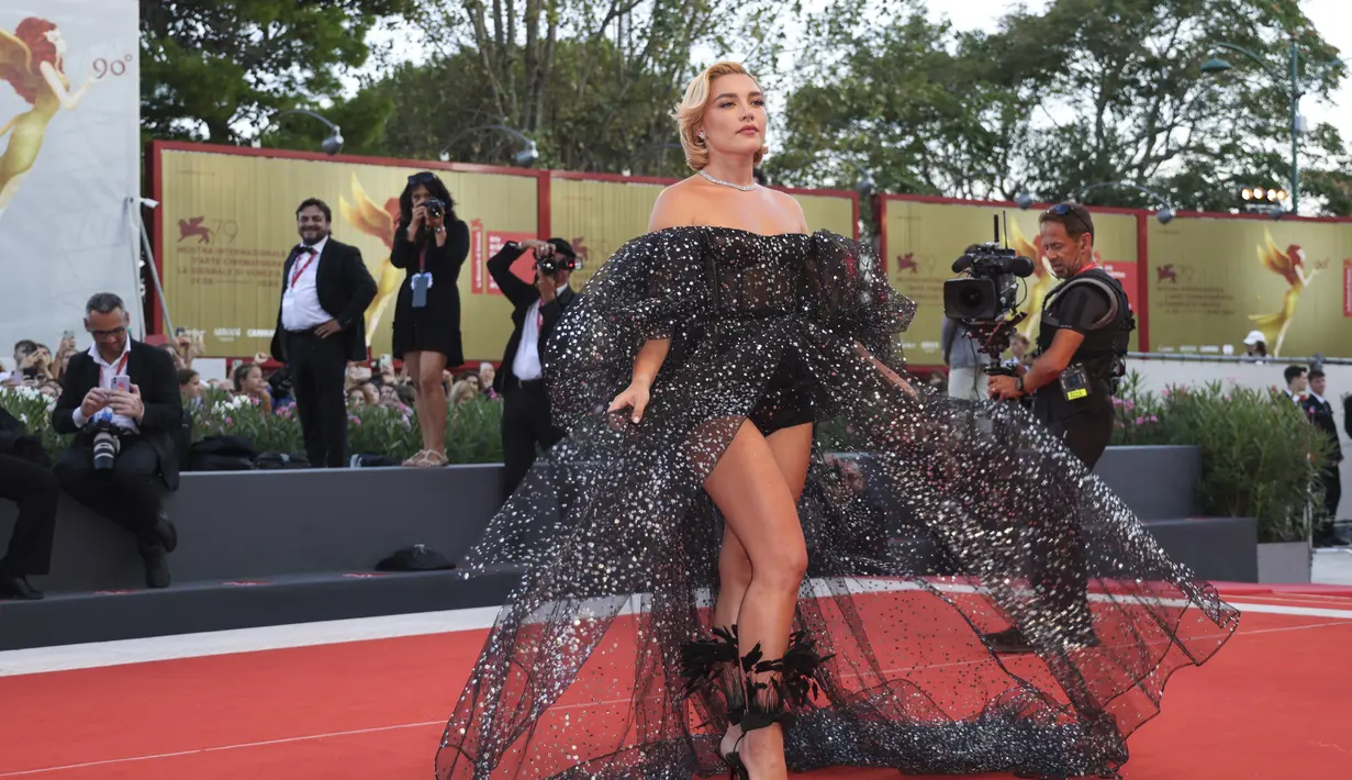Florence Pugh berpose untuk fotografer setibanya di pemutaran perdana film 'Don't Worry Darling' selama Venice Film Festival 2022 ke-79 di Venesia, Italia (5/9/2022). Berasal dari koleksi Haute Couture Fall/Winter 2022-23, Florence memadukan off-shoulder puss sleeve one-piece dengan rok maxi tulle glitter hitam yang dibordir dengan payet perak.  (Photo by Vianney Le Caer/Invision/AP)