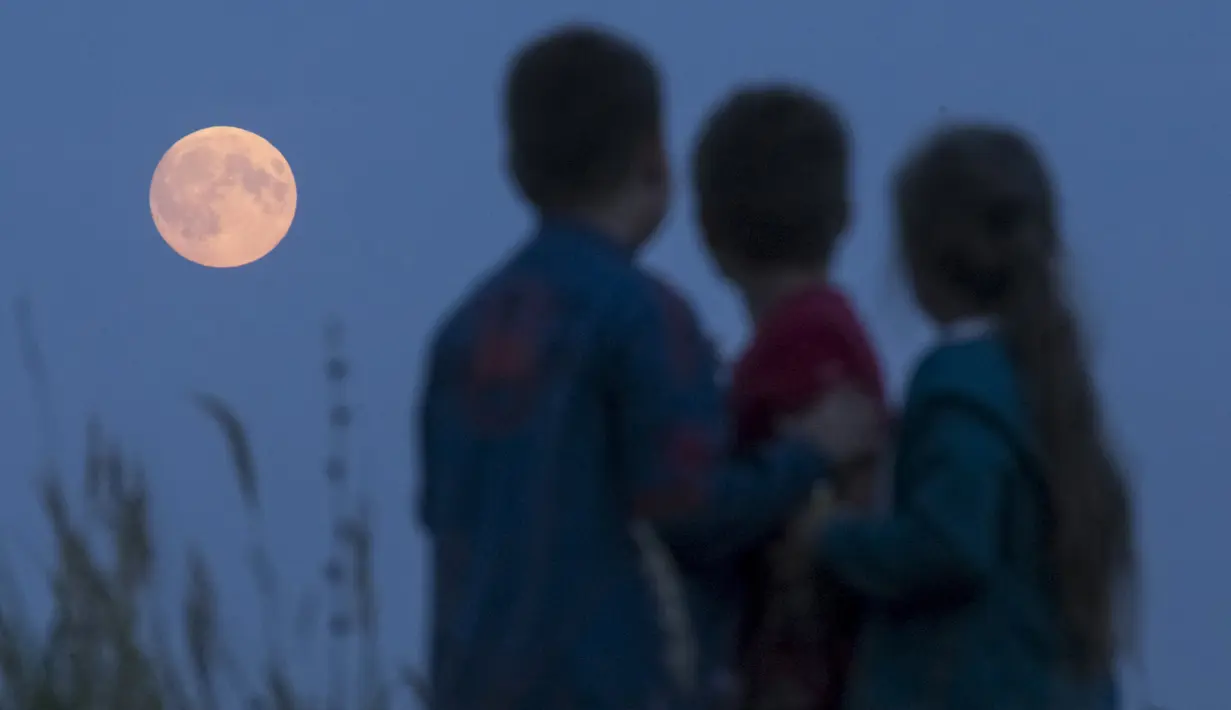 Anak-anak melihat fenomena alam Supermoon di pemukiman Poschupovo di wilayah Ryazan, Rusia, Minggu (27/9). Gerhana Bulan Supermoon (Bulan merah darah) kembali menampakkan keindahannya setelah 18 tahun tidak terjadi. (REUTERS/Maxim Shemetov)