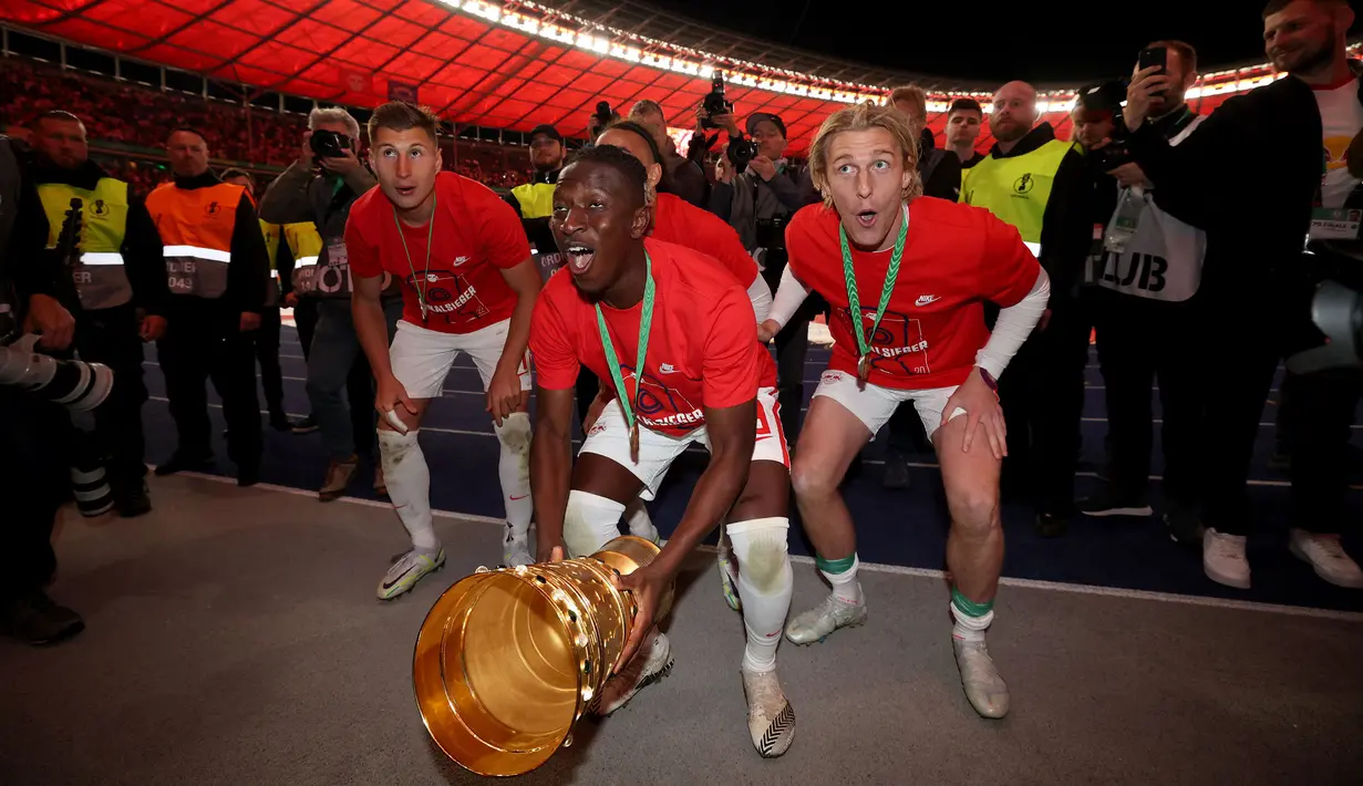 Pemain Leipzig, Amadou Haidara (tengah) merayakan kemenangan dengan mengangkat trofi DFB Pokal atau Piala Liga Jerman bersama rekan setimnya usai mengalahkan SC Freiburg pada partai final yang berlangsung di Stadion Olimpiade di Berlin, Jerman, Sabtu, 21 Mei 2022 waktu setempat. Die Bullen berhasil menang lewat babak adu penalti dengan skor 4-2 usai laga berjalan imbang 1-1. (AFP/Ronny Hartmann)