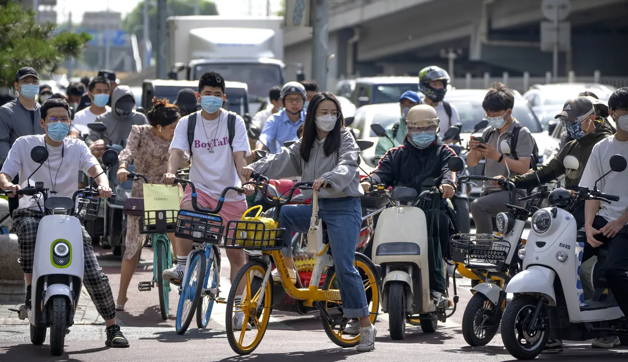 Para komuter yang mengenakan masker menunggu di persimpangan kawasan pusat bisnis di Beijing, China, Selasa (31/5/2022). Otoritas Shanghai mengatakan mereka akan mengambil beberapa langkah besar pada Rabu untuk membuka kembali kota terbesar di China setelah dua bulan penguncian COVID-19. (AP Photo/Mark Schiefelbein)