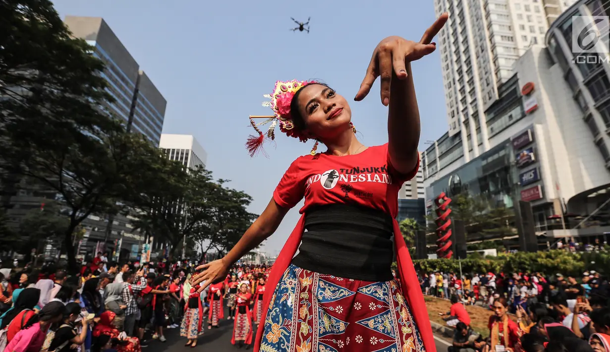 Seorang penari diikuti ribuan peserta membawakan Tari Kembang Jatoh dari Betawi saat CFD di Senayan, Jakarta, Minggu (12/8). Kegiatan ini digelar menyambut HUT Ke-73 RI dan Asian Games 2018. (Liputan6.com/Fery Pradolo)