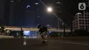 Warga bermain skateboard di jalan lengang kawasan Sudirman, Jakarta, Rabu (12/5/2021) malam. Polda Metro Jaya memberlakukan crowd free night untuk mencegah kerumunan takbir keliling di malam Idul Fitri 1442 yang berlaku mulai pukul 22:00 malam ini. (Liputan6.com/Herman Zakharia)