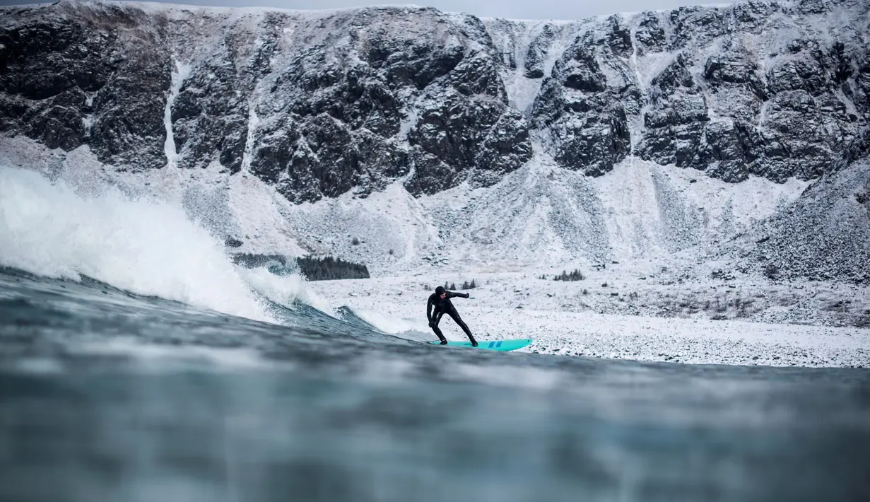 Aksi seorang peselancar diantara hamparan bukit es dan hawa dingin di Lofoten Islands, Norwegia, (10/3/2018). Suhu udara minus 13°C dan suhu diatas air sekitar 4°C. (AFP/Oliver Morin)