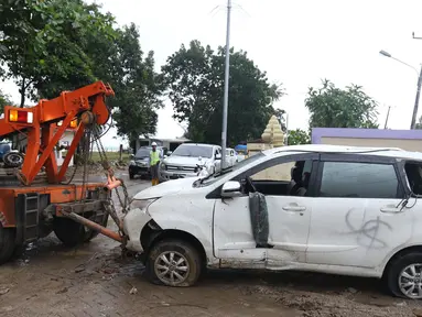 Petugas menderek mobil yang rusak akibat terjangan Tsunami Selat Sunda di Terminal Carita, Banten, Selasa (25/12). Terminal ini dijadikan tempat penampungan mobil yang hancur akibat tsunami. (Liputan6.com/Angga Yuniar)