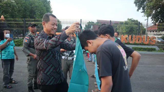 Bupati Kudus Sam’ani Intakoris membagikan celemek kepada sejumlah pedagang kaki lima yang berjualan di kawasan Alun-alun Simpang Tujuh Kudus. (Liputan6.com/Arief Pramono)