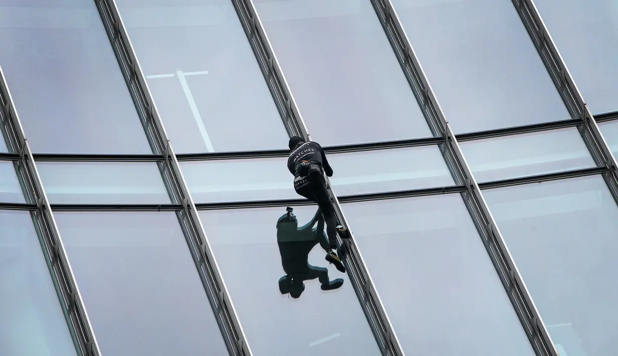 Pendaki kota Prancis, Alain Robert saat berusaha memanjat gedung XYZ di Frankfurt am Main, Sabtu (28/9/2019). Alain yang dikenal sebagai "The French Spiderman" kembali memanjat gedung tinggi di kota Jerman tersebut. (AFP Photo/Daniel Roland)